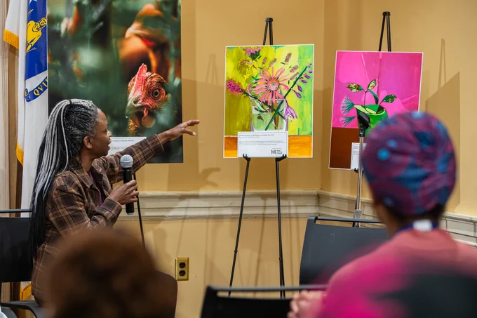 Artist gesturing at artwork. 