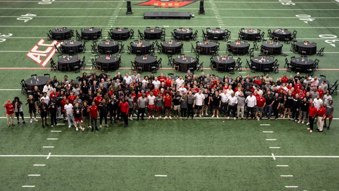 A group photo of Louisville football players, staff and alumni.