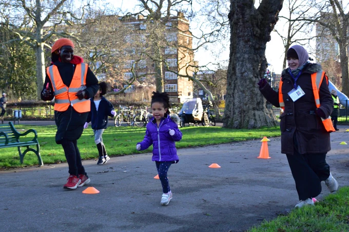 Two volunteers parkrunning with a junior parkrunner at the finish funnel