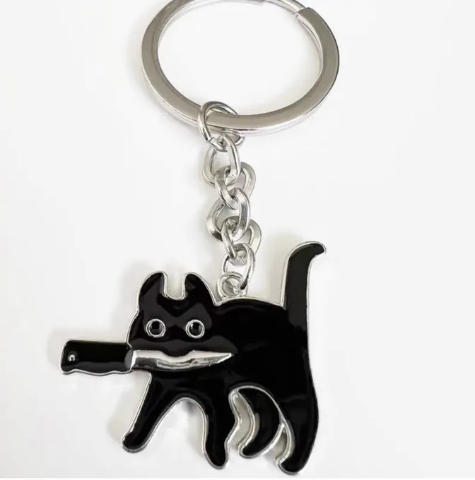 Keyring of a black cat with a silver knife in its mouth.