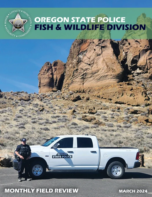 A police officer stands in front of a white truck with Fort Rock and blue sky in the background.