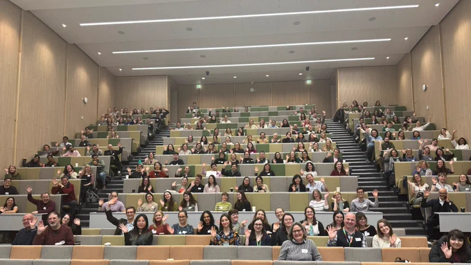 Photo of a lecture theater with the audience waving