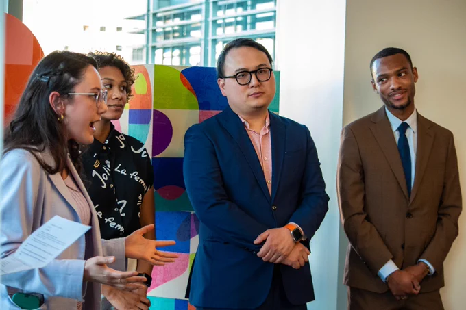 Congressional staffers speak to an unseen audience in front of colorful blocks