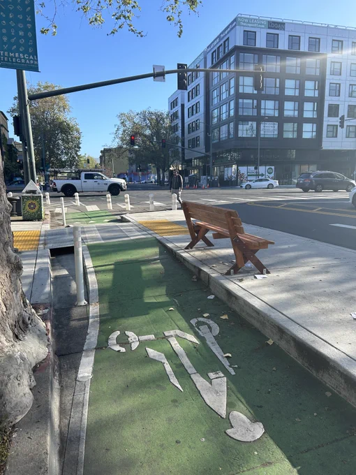 Bench provided by people at a floating bus stop, with a bike lane.