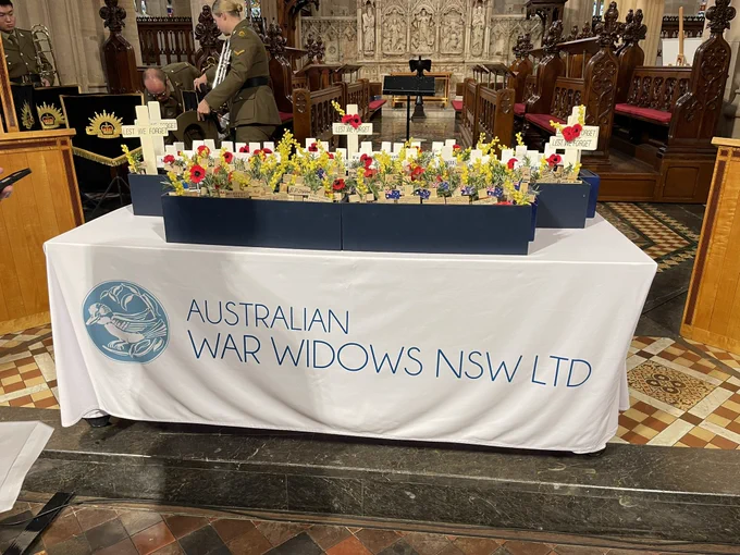 Table with Australian War Widows NSW tablecloth covered in crosses with poppies on them.