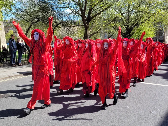 Red clad people processing along a street.