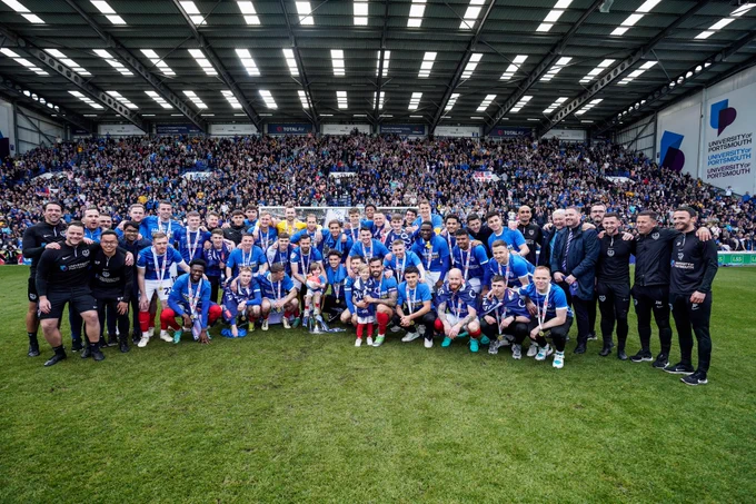 Pompey players and staff with the League One trophy in front of the Fratton End.