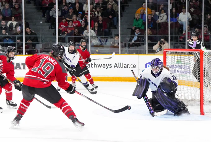 Brianne Jenner shooting on MIN goaltender Nicole Hensley. She is wearing her red PWHL Ottawa uniform.