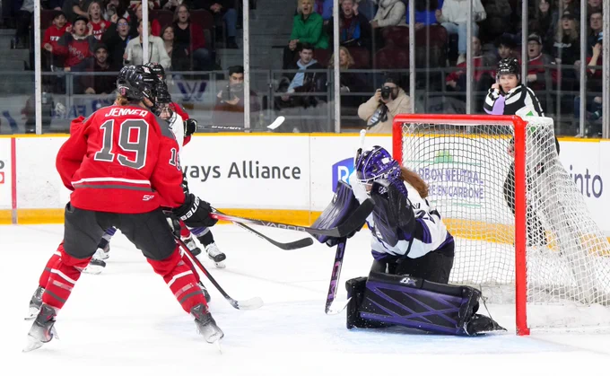 Brianne Jenner scoring on MIN goaltender Nicole Hensley. She is wearing her red PWHL Ottawa uniform.