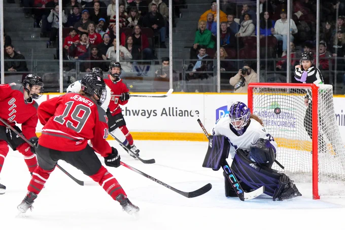 Brianne Jenner shooting on MIN goaltender Nicole Hensley. She is wearing her red PWHL Ottawa uniform.