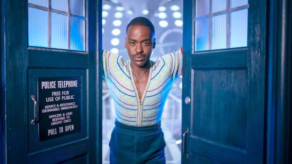 Ncuti Gatwa season 1 promo photo in blue striped top standing in tardis door way