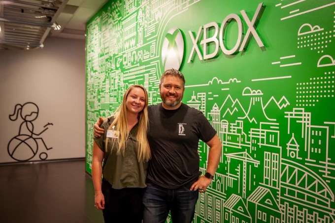 Dr. Jones and Dr. Johnson stand with their arms around each other in front of a green wall with Xbox on it.