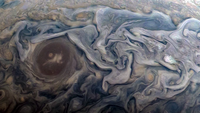 Image description: An image split in two shows blue, white, and tan clouds and storms swirling in Jupiter's atmosphere. The clouds flow and curve gently around each other as they etch across the planet. Credit: Enhanced image by Kevin M. Gill (CC-BY) based on images provided courtesy of NASA/JPL-Caltech/SwRI/MSSS