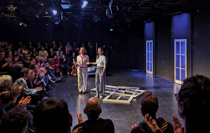 Two performers on a stage during an applause.