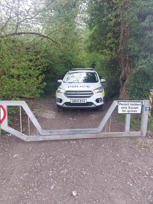 Police car parked in a gate entrance  to a bridleway