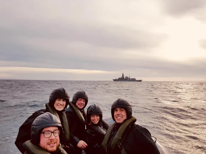 Sailors in a rigid inflatable boat patrolling waters and smiling for the camera whilst doing so