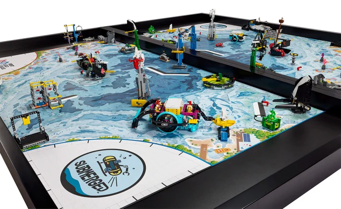 robotics competition board with blue underwater theme; LEGO builds on top