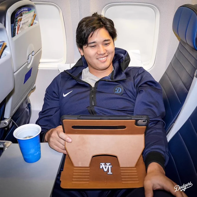 Shohei Ohtani smiles while watching his tablet.