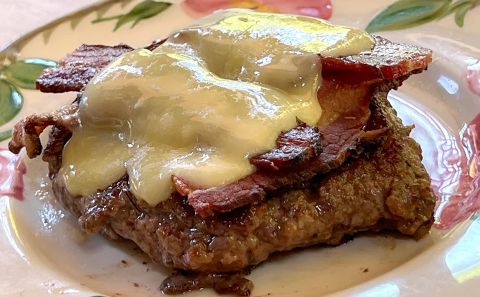 Bunless LeftCoast GrassFed burger topped with cheese and Root Down Farm bacon