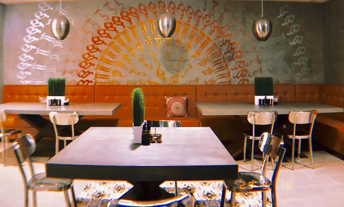 Tables with chairs and accents. Large colorful mandala mural on wall at Lexen Hotel North Hollywood.