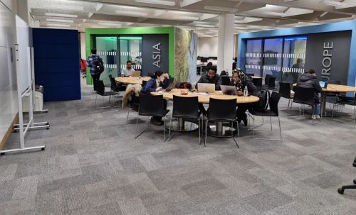 Image of the inside of Dundee University Library. Students sit around a table studying. 