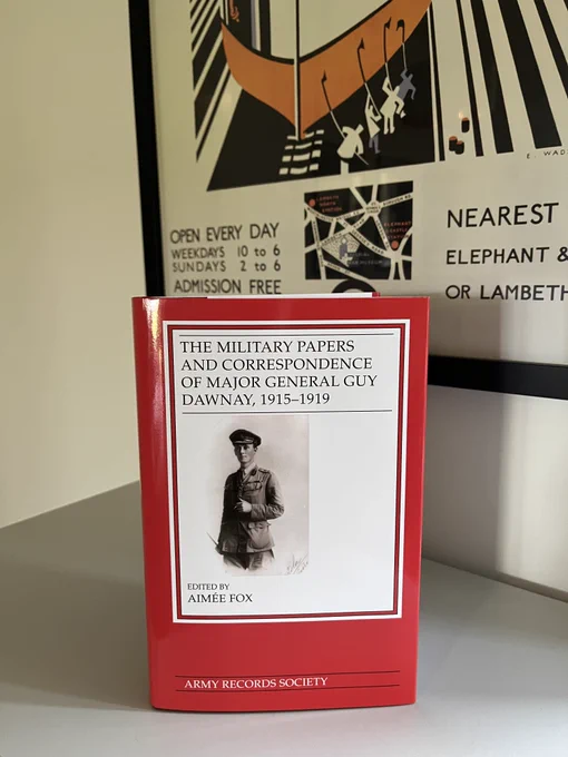 A red jacketed book sits on a grey table top against the backdrop of a vintage London Underground poster, advertising the Imperial War Museum.

The book is titled 'The Military Papers and Correspondence of Major General Guy Dawnay, 1915-1919'. Below the title is a sepia photograph of a British army officer, holding a cigarette.