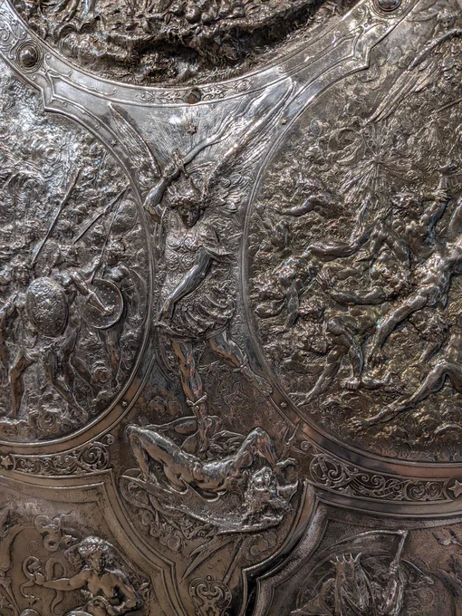 A detail on the shield, showing an armoured angel holding a sword and standing on a cowering devil