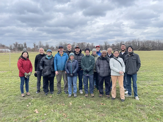 A group of scientists of various races and genders in warm winter clothing standing in a field