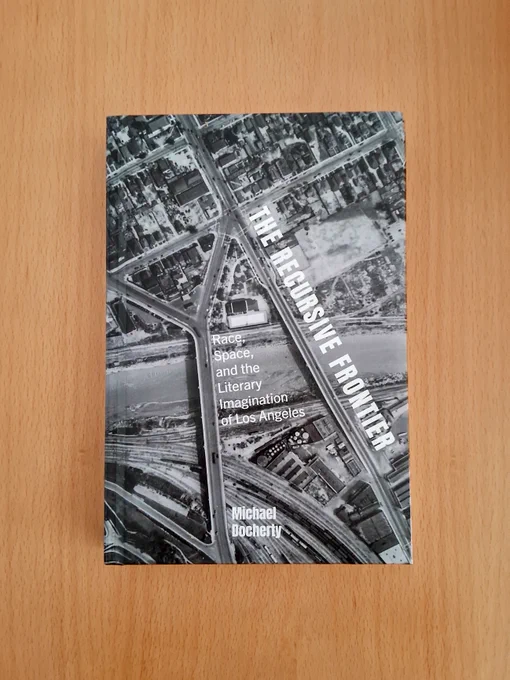 Photo of a book cover: "The Recursive Frontier: Race, Space, and the Literary Imagination of Los Angeles," by Michael Docherty. The cover image is a black and white aerial image of Los Angeles.