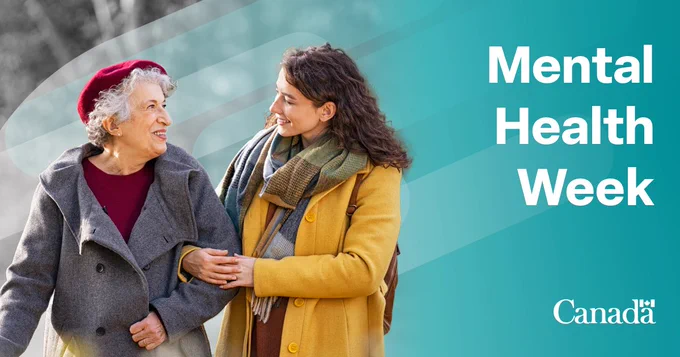 A person holding onto another person’s arm while they look and smile at each other on a blue and grey background. The text on the right of the image reads “Mental Health Week”. 