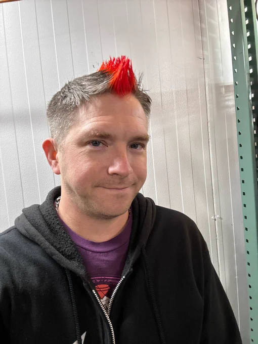 Picture of Martini with a bright red Mohawk wearing a black zip up hoodie