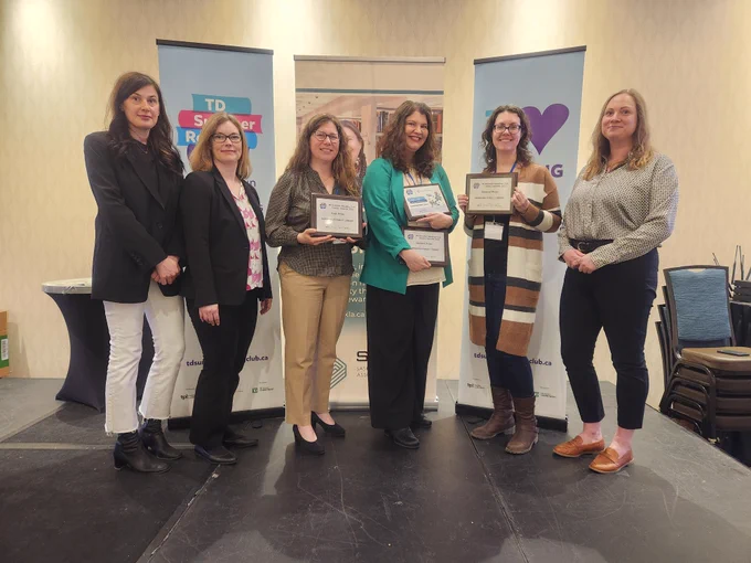 Winners of the 2023 TD Summer Reading Club Library Awards receiving their awards at the Saskatchewan Library Association Conference.

From left to right: Jessica Roy (TD Summer Reading Club), Rachel Breau (CELA Library), Pam Hudson (Gananoque Public Library), Andrea Siemens (Cambridge Public Library), Amber Lamboo (Winnipeg Public Library), and Ashley-Ann Brooks (Library Archives Canada). 