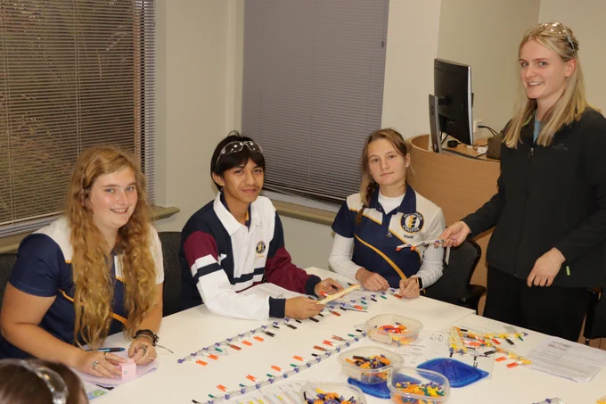 Students with instructor with DNA replication models on table in foreground