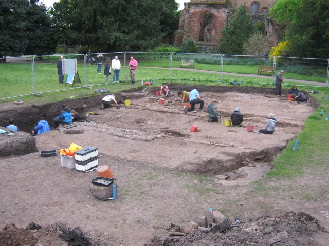 A view of the whole excavation trench with students at work; the ruins of the east end of St John's Church are in the background. The trench is 25m x 20m.
