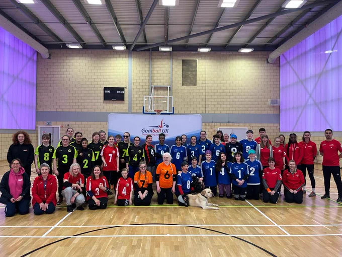 A wide group photo in a sports hall showing all of the teams from the 2023 TGC Open
