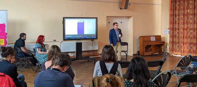 Innovate Trust CEO Nick French standing in front of a screen, presenting to a room of people