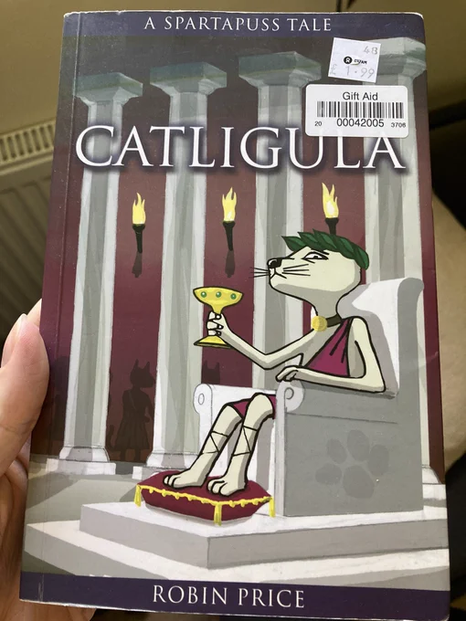 An image of a book titled “Catligula” with the tagline “A Spartapuss Tale”. The book is by Robin Price, and the cover art features a cat dressed in a purple toga, holding a golden goblet and sitting on a throne.