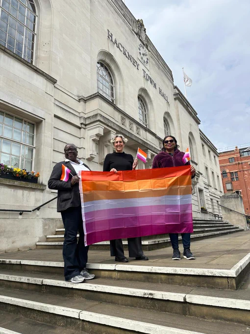 Group photo with Cabinet Members Cllr Williams and Cllr Etti holding a banner and flags to mark Lesbian Visibility Day