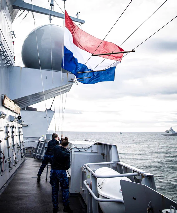 Crew with the Koninklijke Marine raise the Netherlands flag on a ship out at sea during exercise Joint Warrior 23. Photo by: Koninklijke Marine