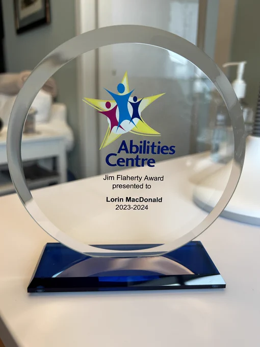 An award designed with a clear circle that has the Abilities Centre logo, and the words Jim Flaherty Award presented to Lorin MacDonald 2023-2024.