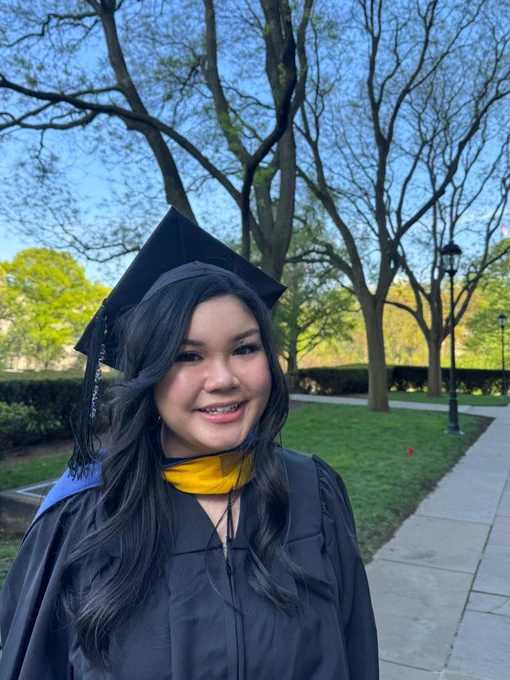 Leann wearing graduation cap and gown while standing outside on Pitt campus