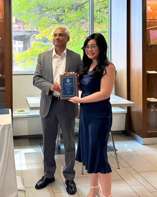 Dr. Padiath awarding Leann with a plaque titled "Chair's Special Award for Social Justice and Advocacy in Genetics" at Pitt Public Health