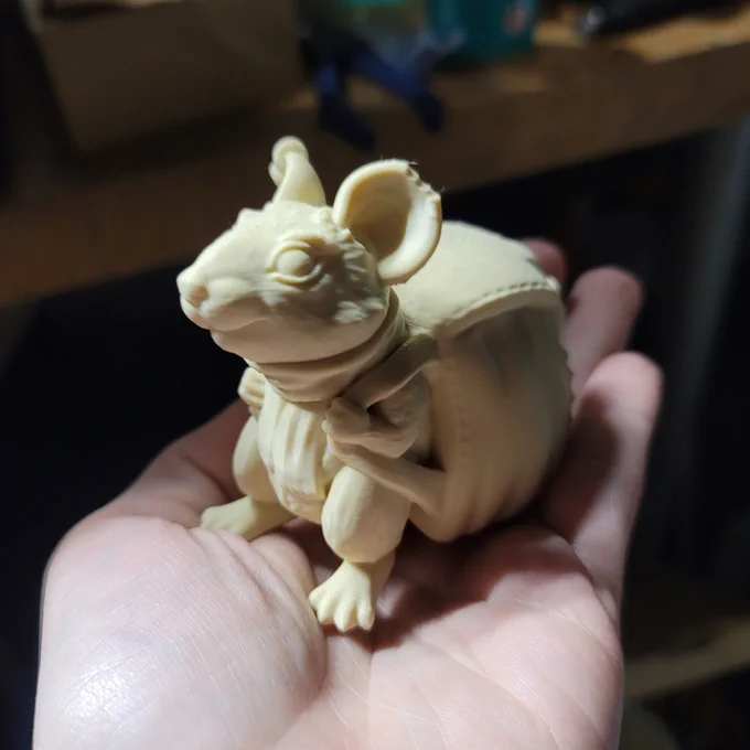 An FDM 3D print of an anthropomorphic Pack Rat, wearing a large bag on his back, being held in a hand.