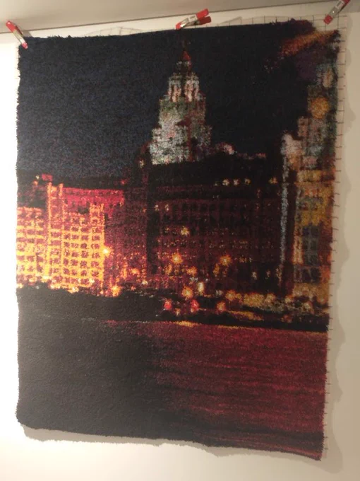 Large rag rug depicting part of the Liverpool waterfront at night time.