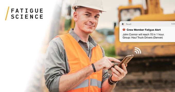 A worker wearing a safety vest and hardhat holds a cellular phone. Text on image reads: Fatigue Science - Crew Member Fatigue Alert.