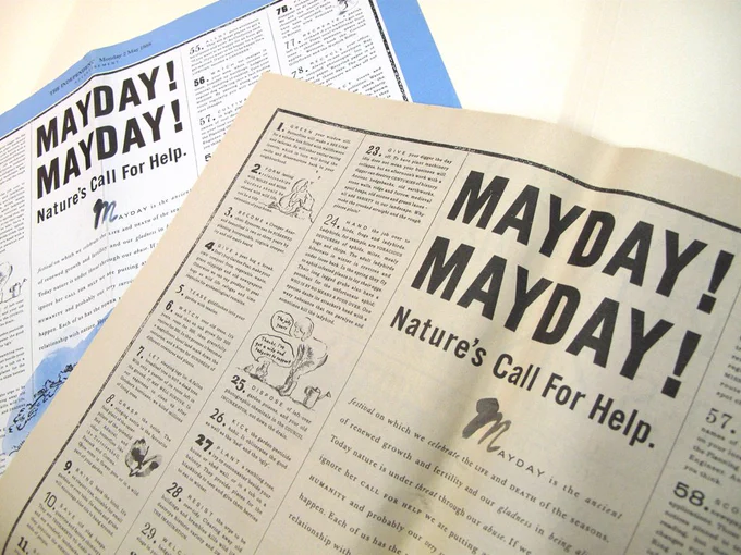 One newspaper-printed poster lying on top a colour poster, photographed at an angel. The poster is entitled 'Mayday! Mayday! Nature's Call for Help.'