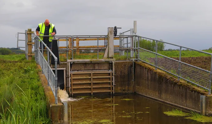 An IDB staff member adjust a water control structure