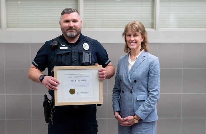 From left: Investigator Scott Parker and Mayor Leirion Gaylor Baird stand side by side smiling after Parker received the Mayor's Award of Excellence. 