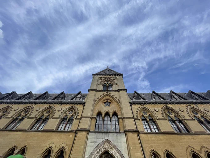 A view looking up at the front face of the museum, a Neogothic Victorian building with many decorative carvings