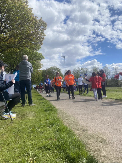 A crowd of people with various charity tops on taking part in the Glasgow Kiltwalk 2024 on a very sunny day